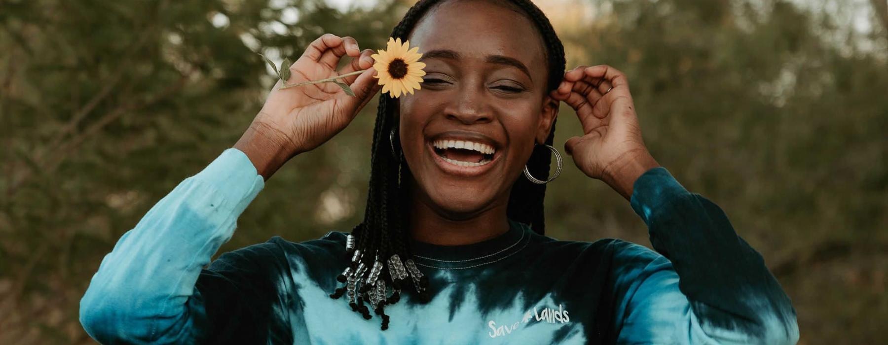 woman holds a flower in her hair in a park